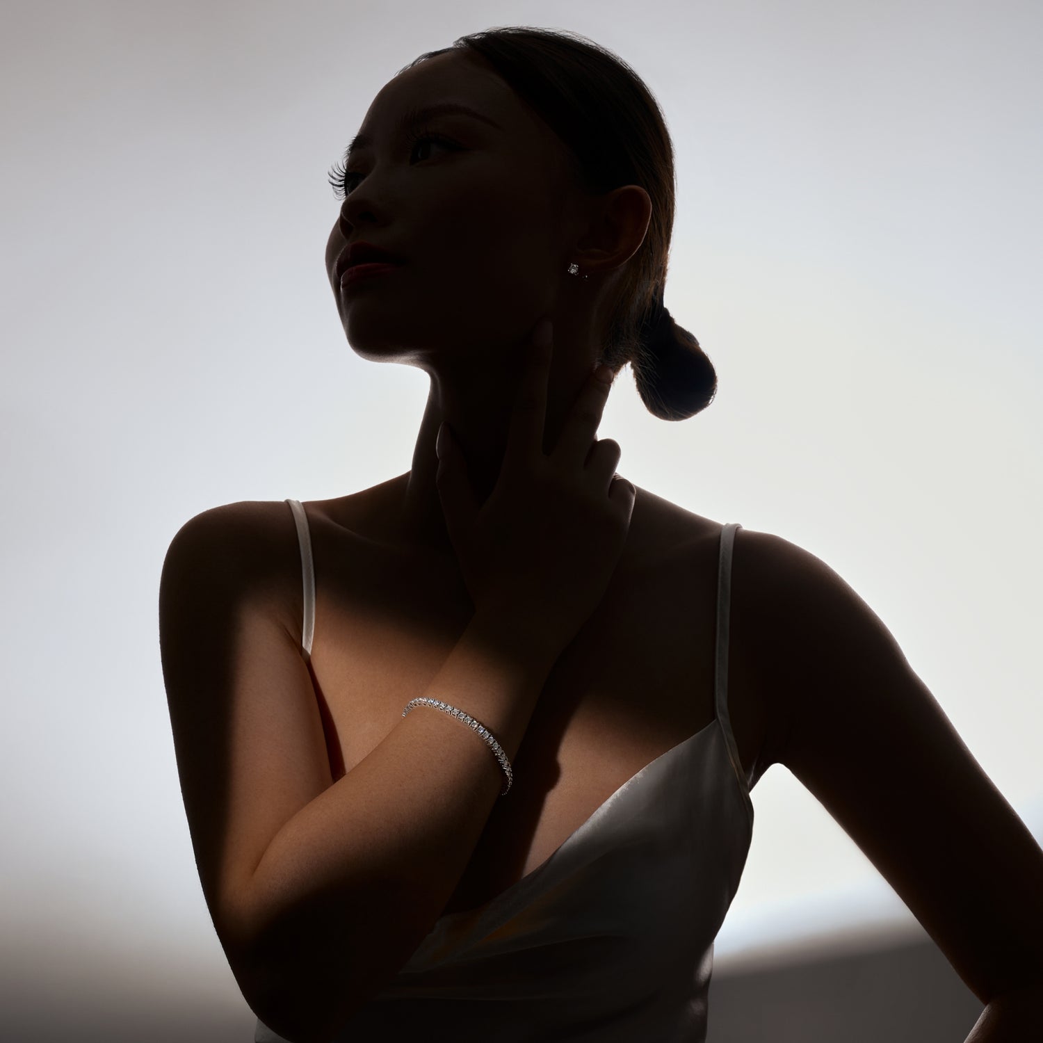 classically beautiful woman wearing stunning moissanite bracelet and earrings in the shadows