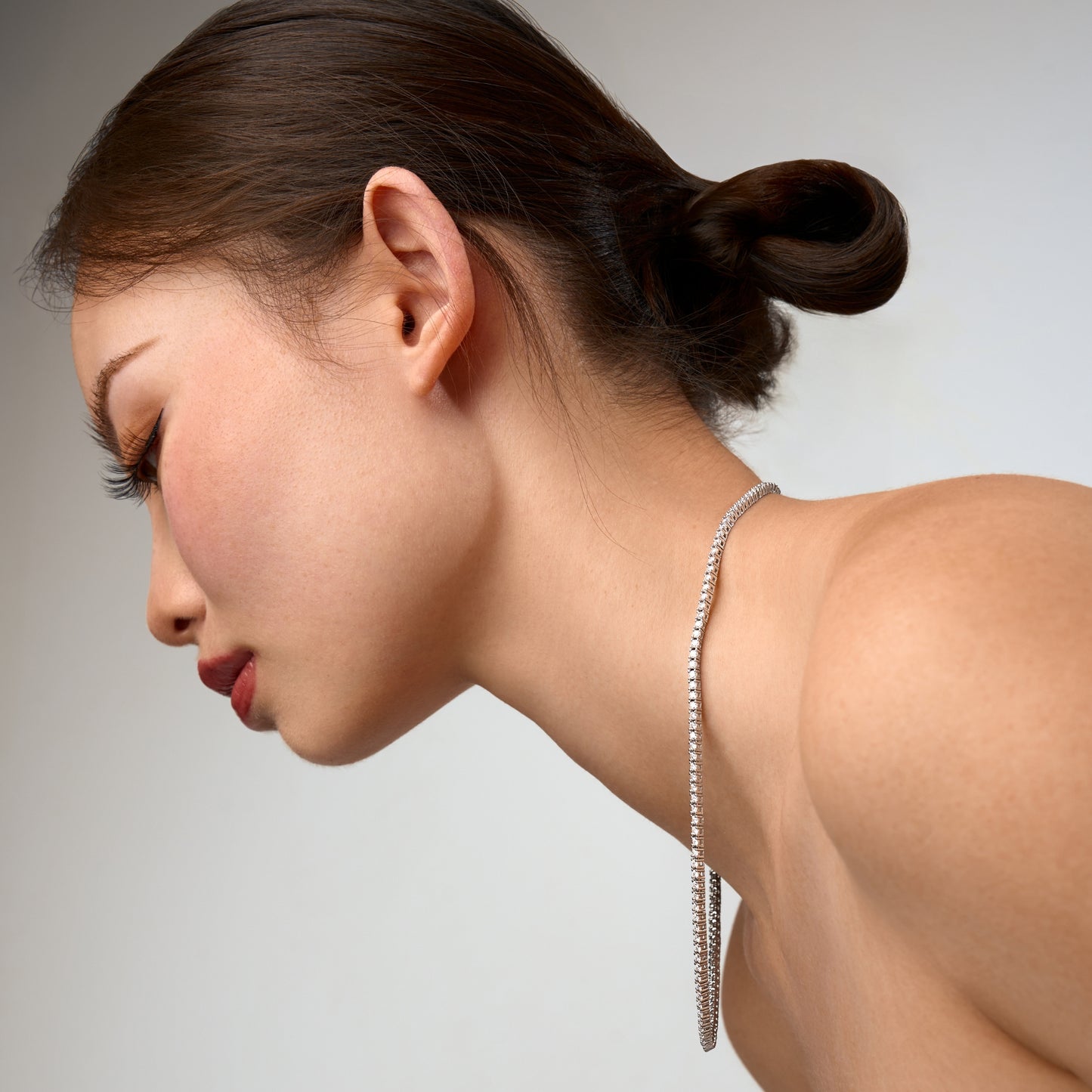 Woman wearing a moissanite necklace against a neutral background