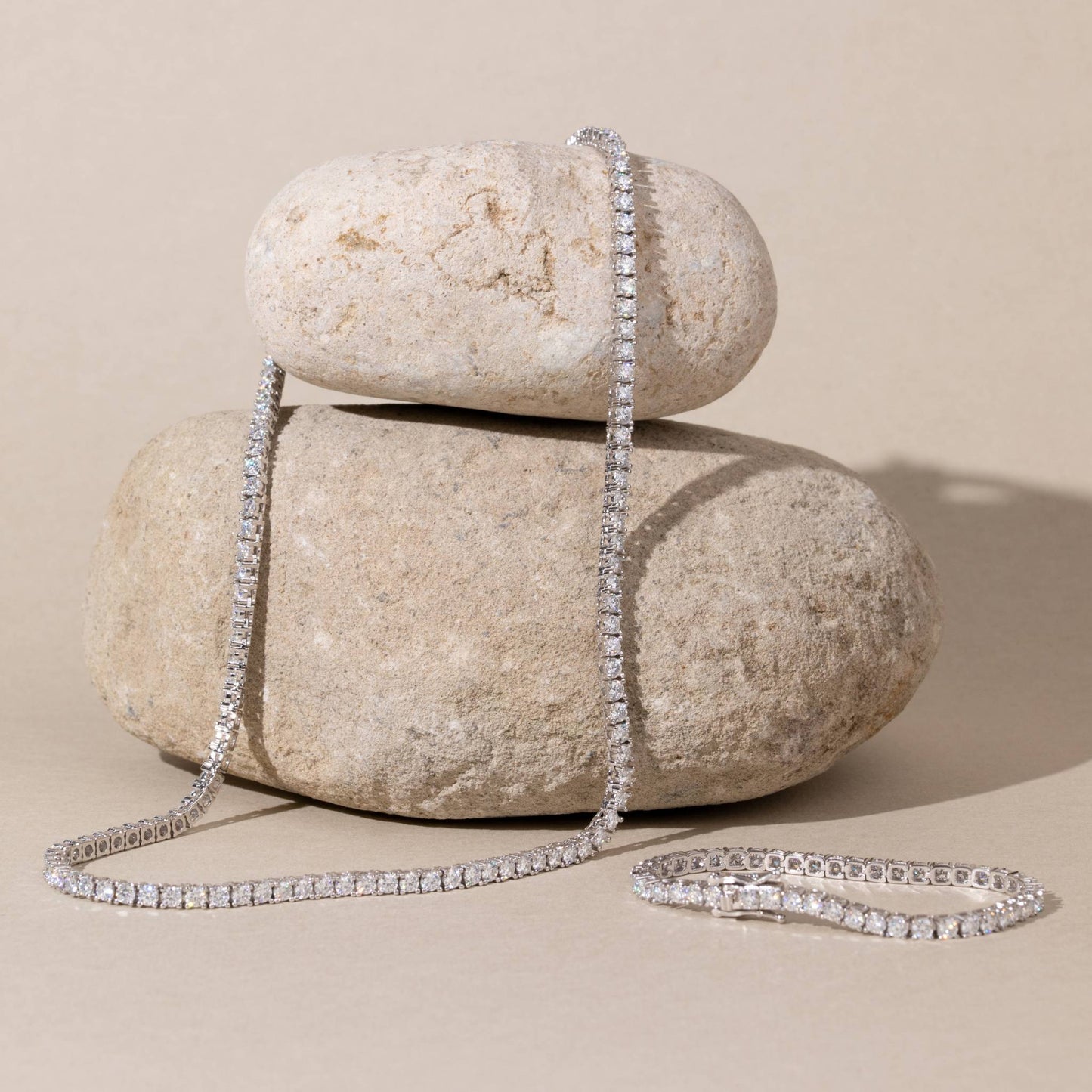 Moissanite necklace draped over two stacked stones on a beige background