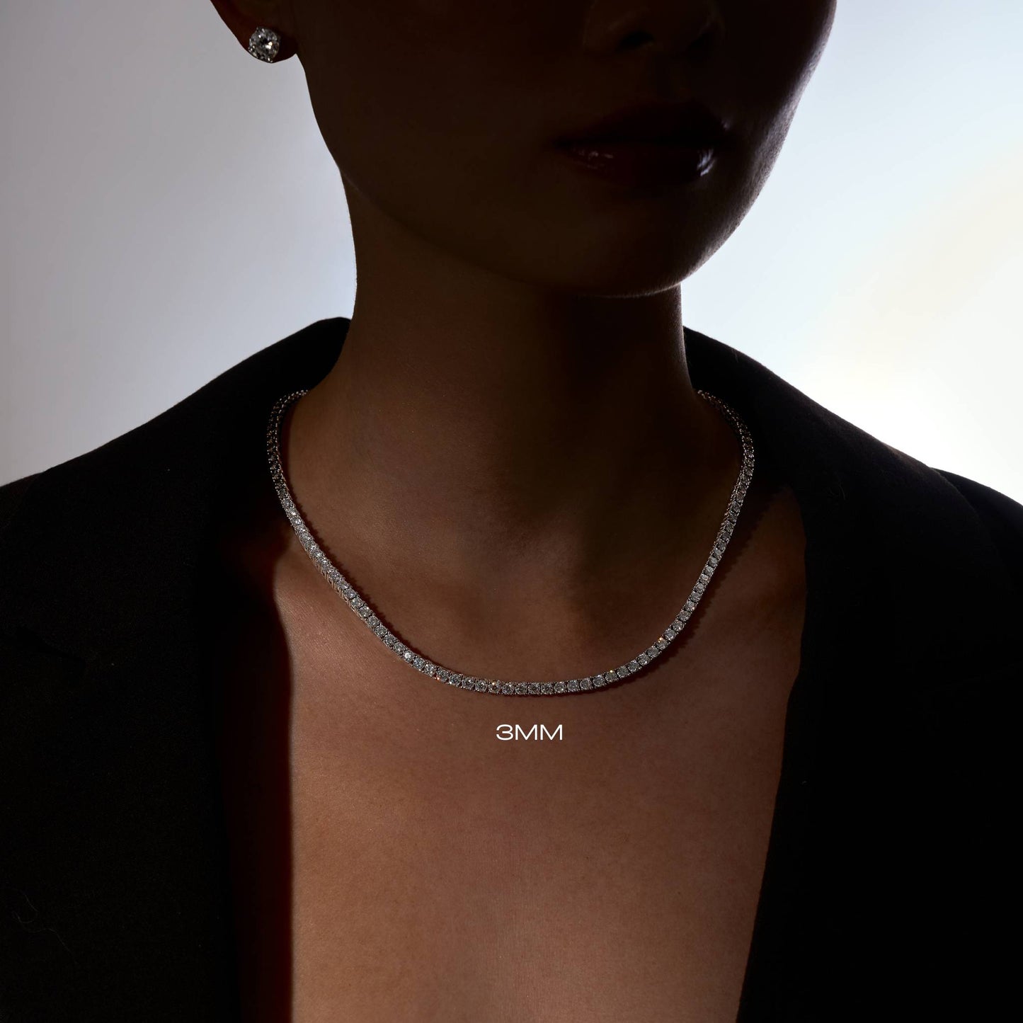 Person wearing a moissanite 3mm tennis necklace on a neutral background