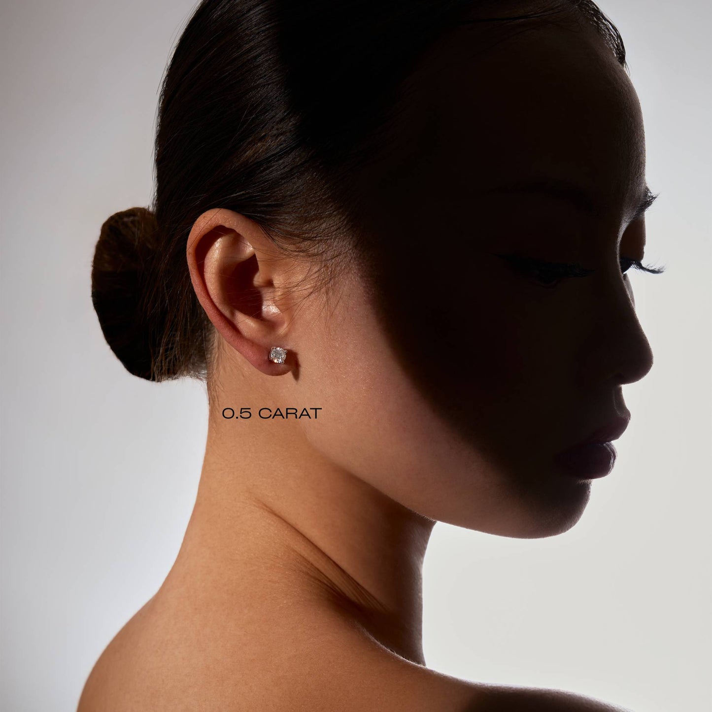 Side profile of a woman wearing a diamond earring with '0.5 CARAT' text.