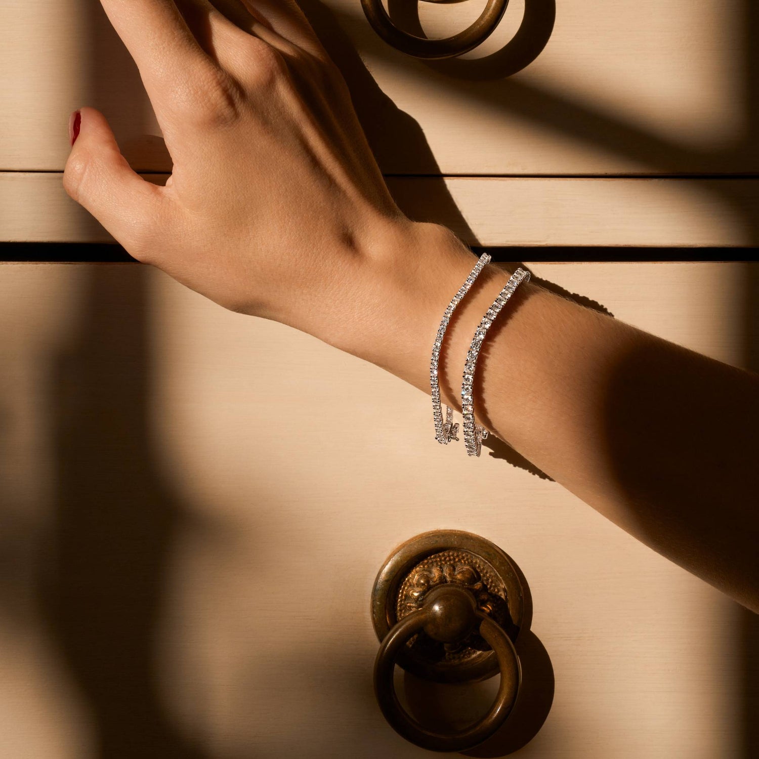 Hand with moissanite gold plated bracelets on a door handle