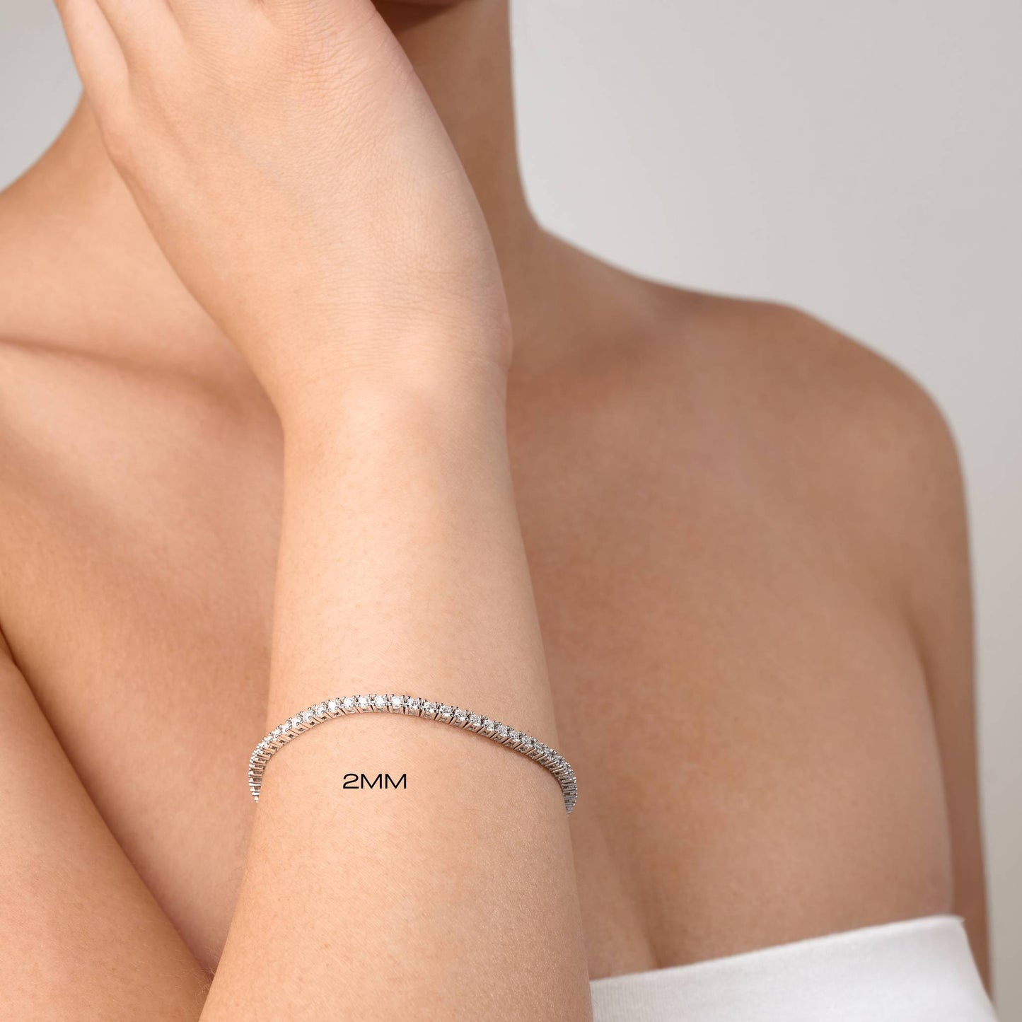 Silver bracelet on a person's wrist with '2MM' text, against a neutral background