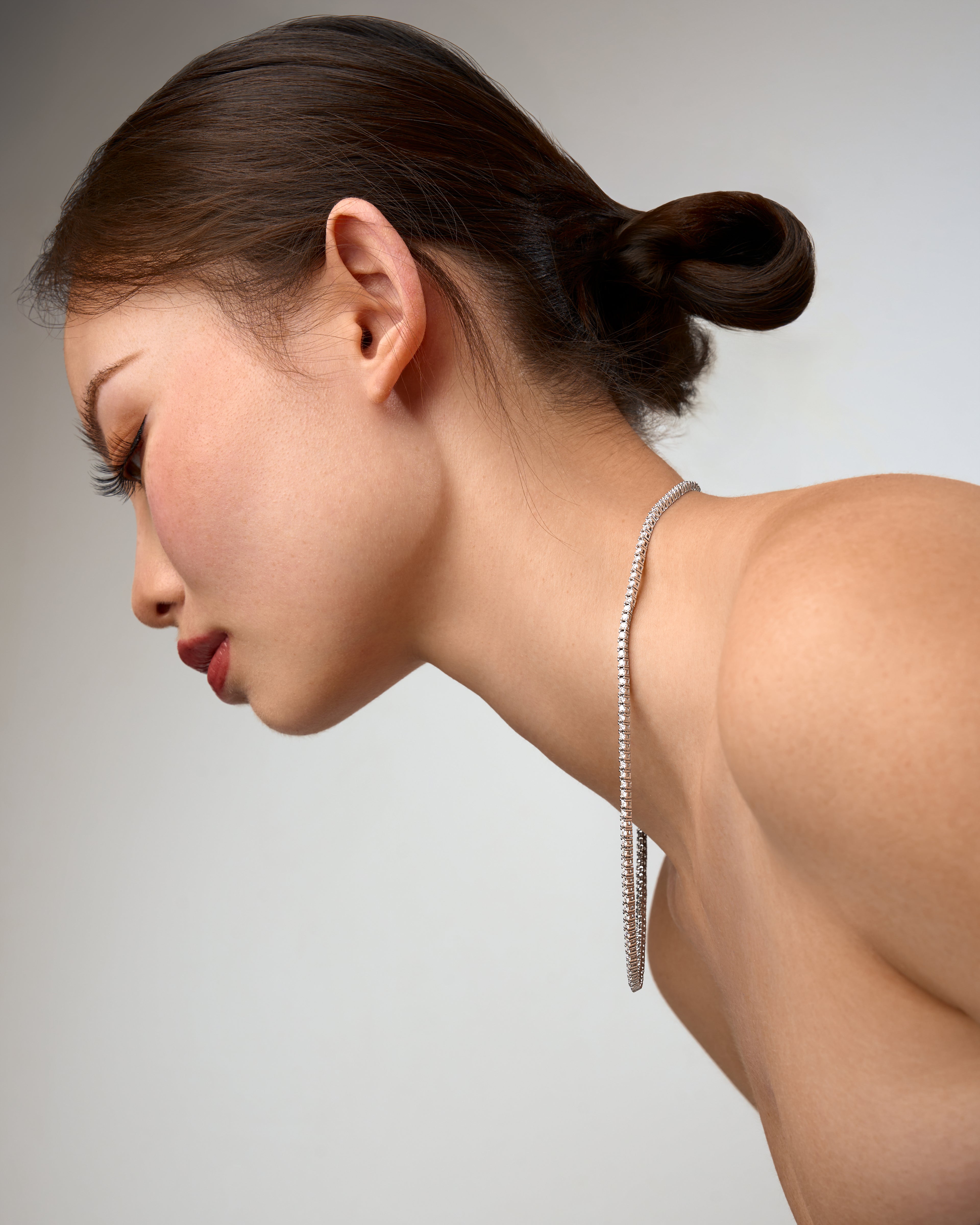 Woman wearing a silver moissanite necklace against a neutral background
