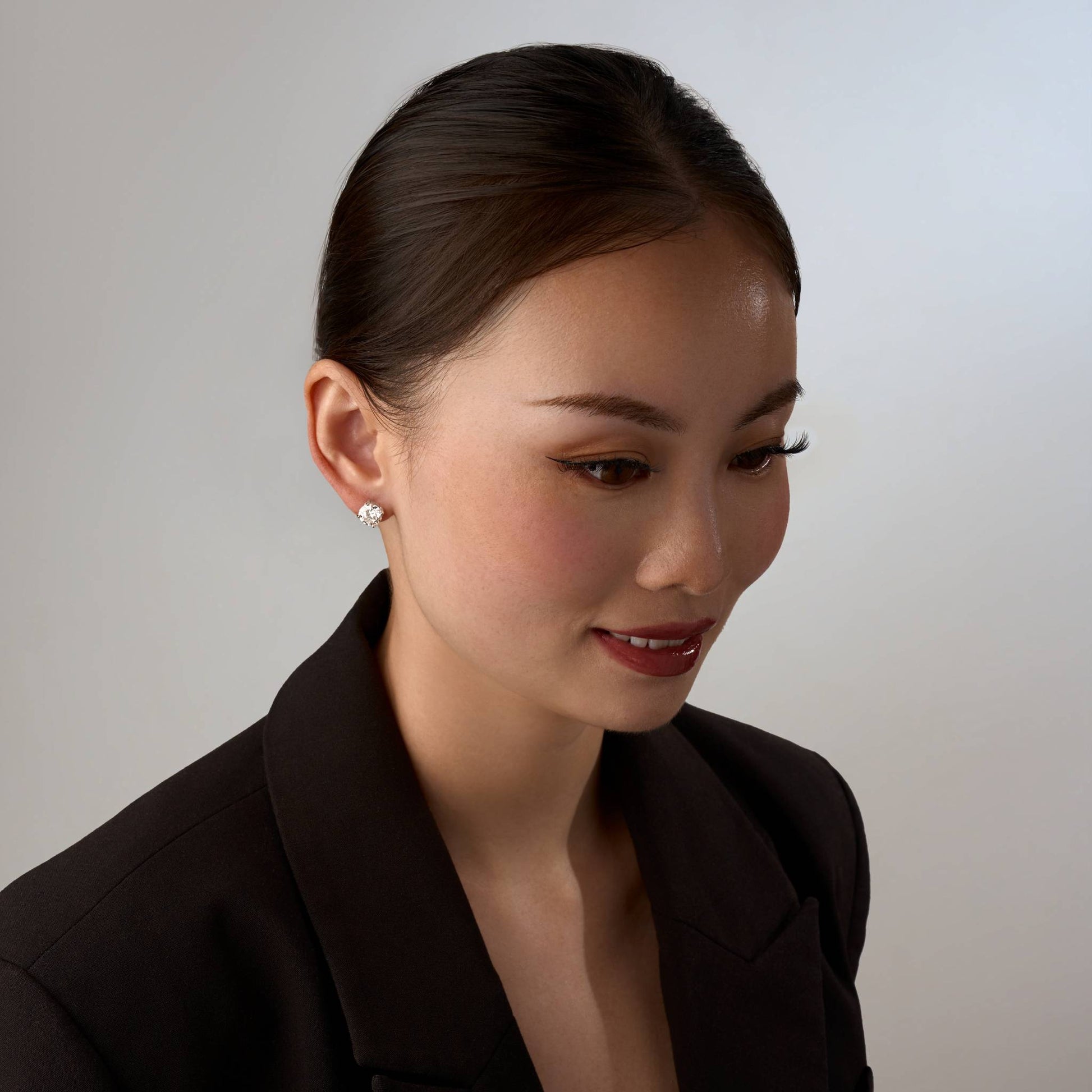 Woman wearing a black blazer against a plain background with 2CT earrings