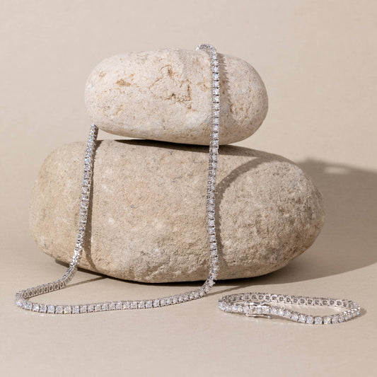 Moissanite necklace draped over two stacked stones on a beige background