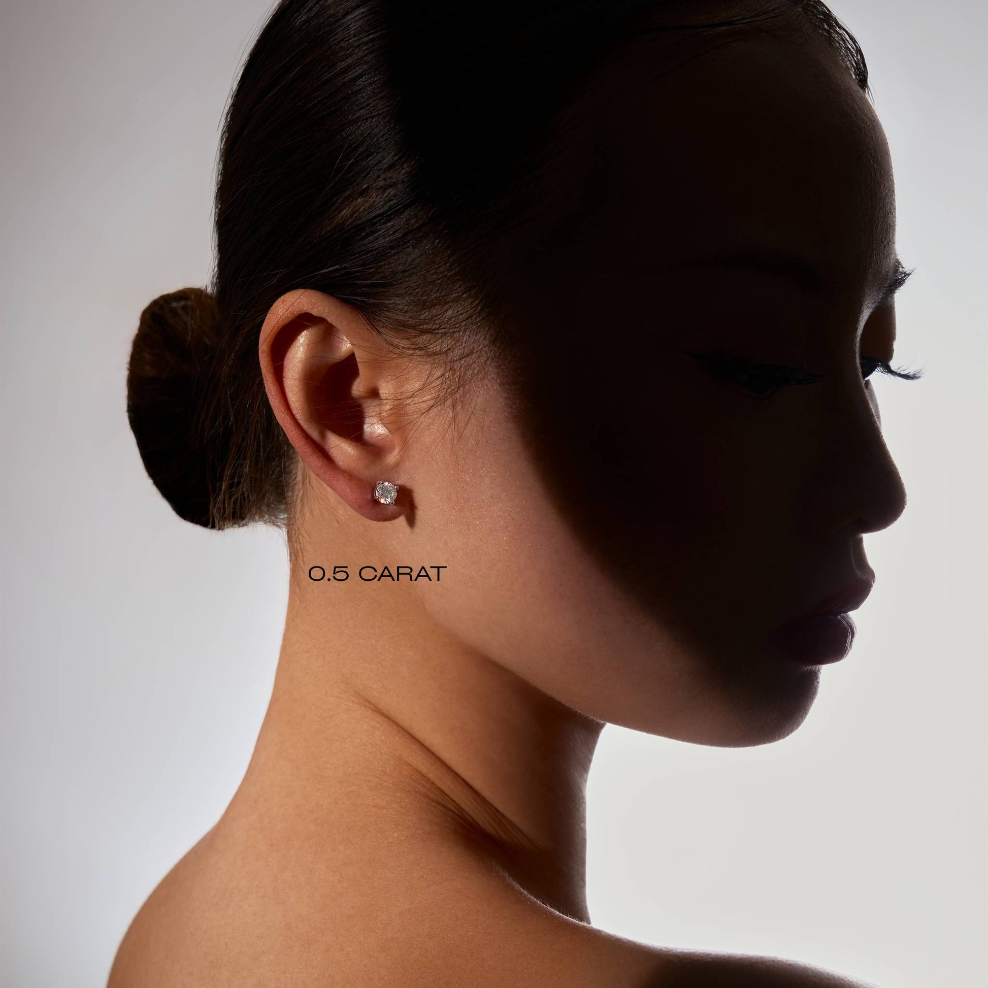 Side profile of a woman wearing a diamond earring with '0.5 CARAT' text.