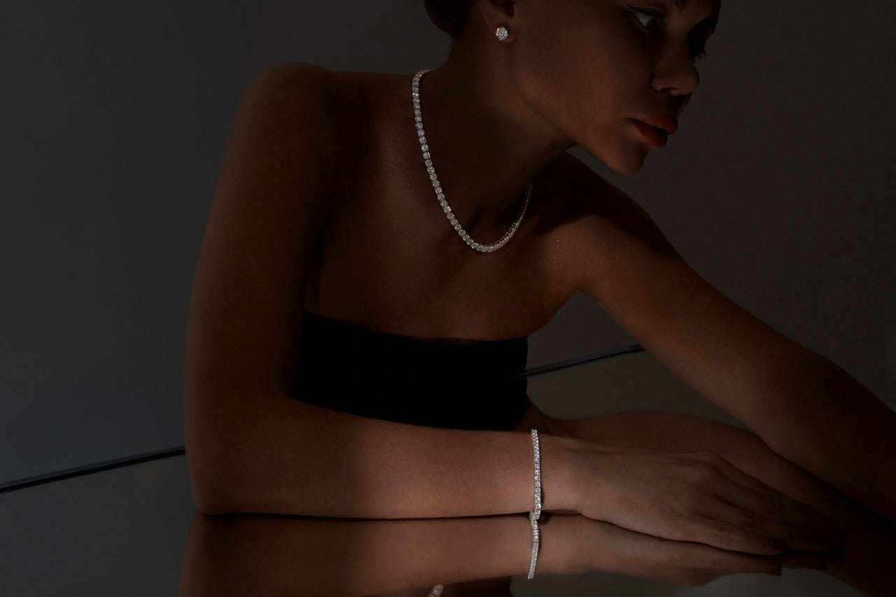 Woman wearing a black strapless top and sparkling moissanite jewellery against a dark background